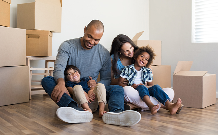 Smiling and happy family sitting on the floor with moving boxes.