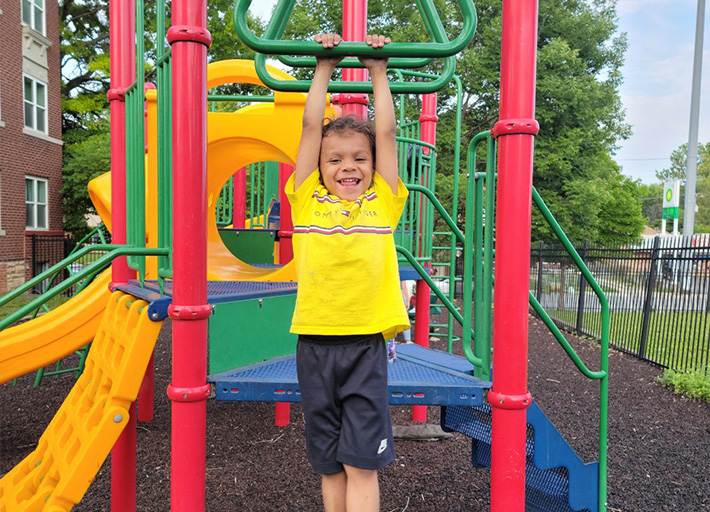 A smiling child playing on a colorful playground.