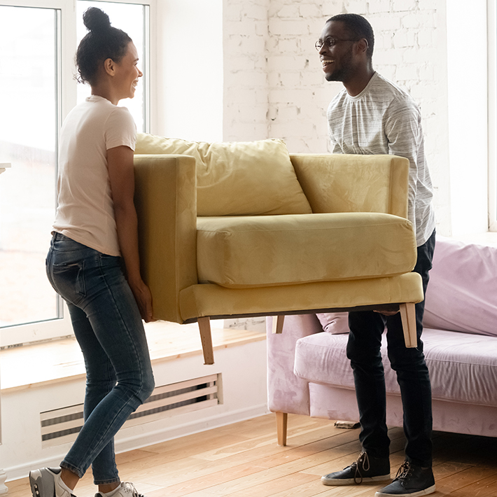 Two people moving a yellow chair.