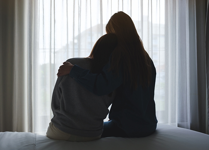 A woman leaning on another person's shoulder receiving comfort.