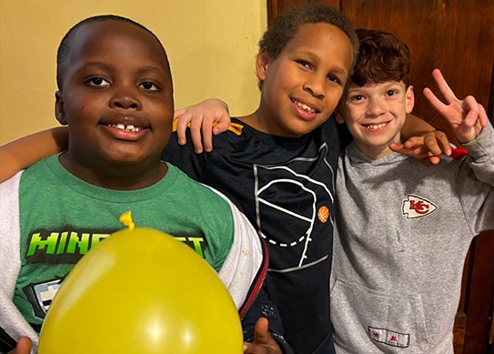 Three kids who are close friends smile for a picture