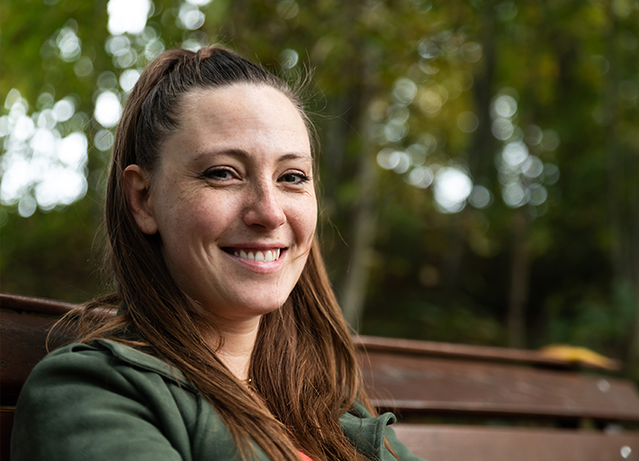 A smiling woman on a park bench.