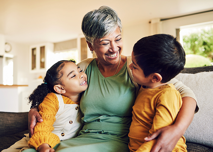 A grandma hugs her grandson and granddaughter on a couch