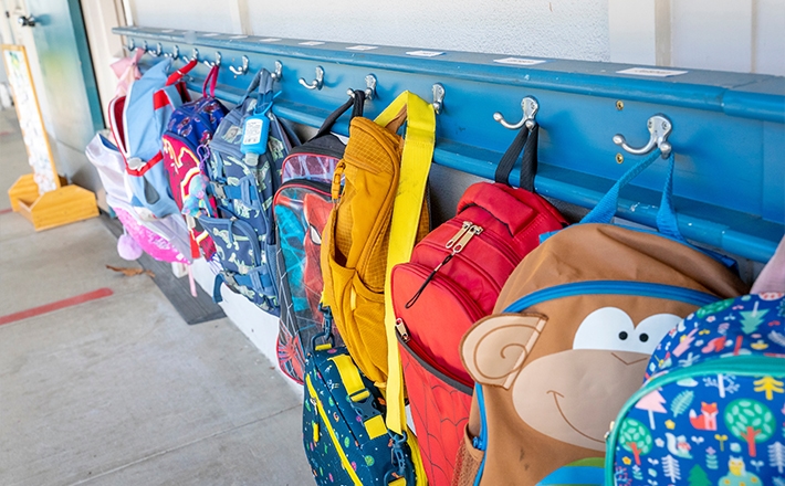 Children's backpacks all hanging in a row