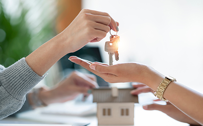 A realtor hands the keys to a new home to their client
